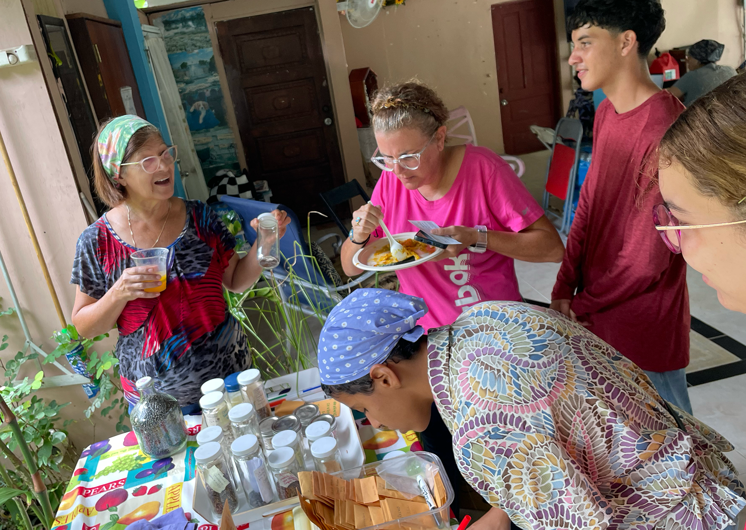imagen de varias vecinas de San Salvador e integrantes del Depa, compartiendo alrededor de una mesa con semillas y sobres durante una actividad de apoyo al barrio y sus agricultores post-Fiona