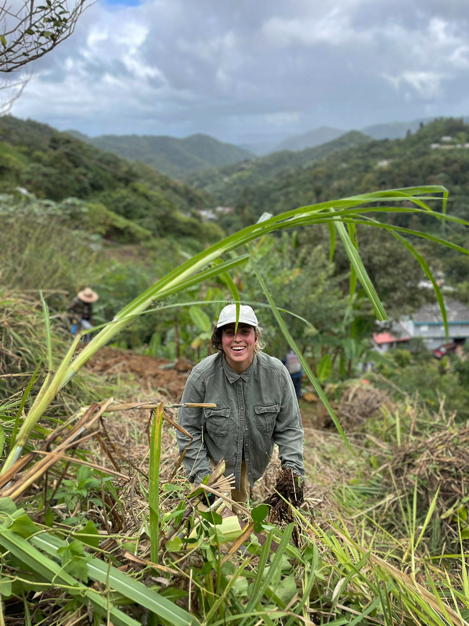 Imagen de persona trabajando en una loma con grama alta en el campo.